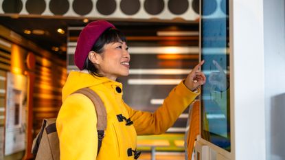 Woman about to touch large touchscreen in fast food restaurant