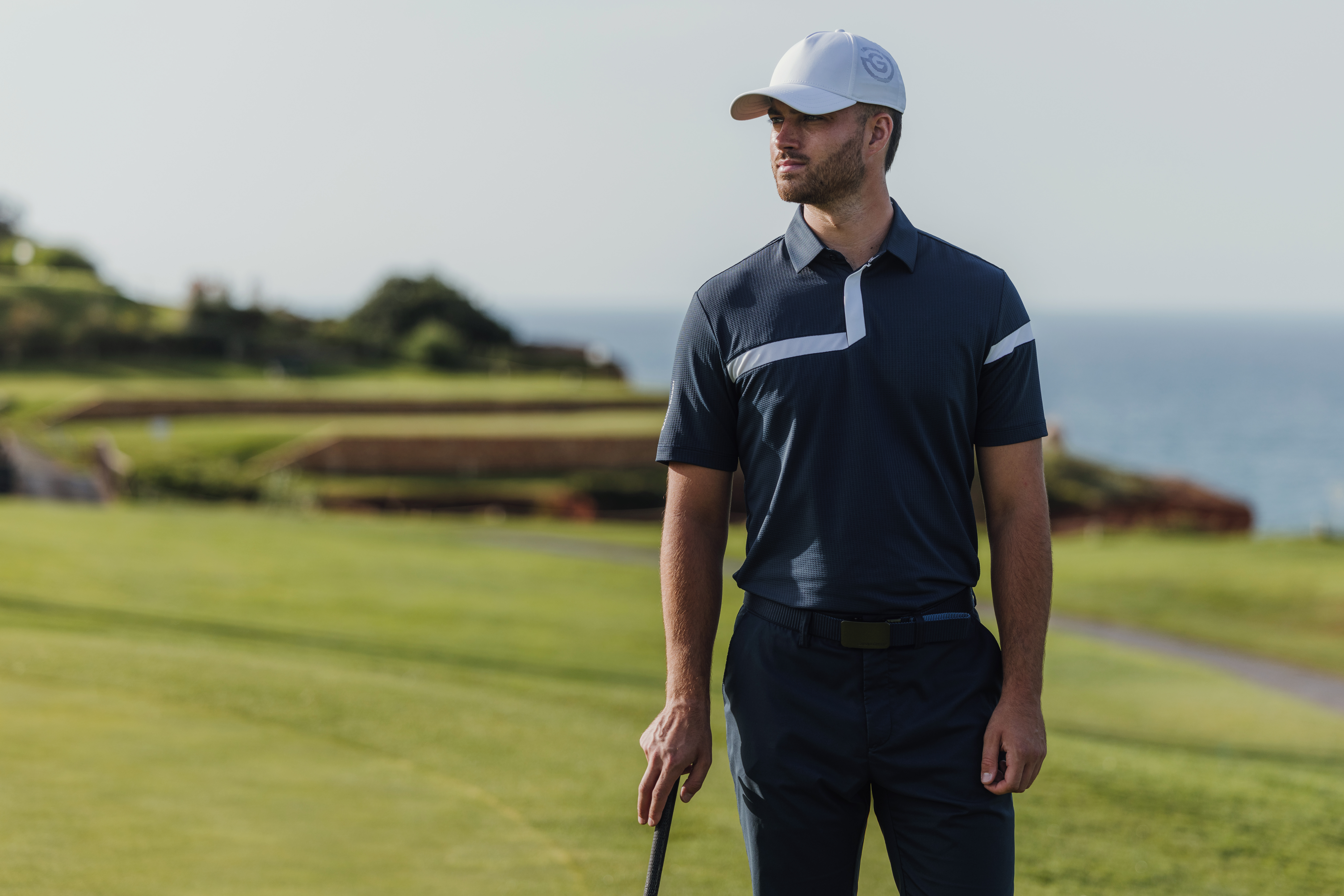 A golfer holding a club while wearing a polo and cap