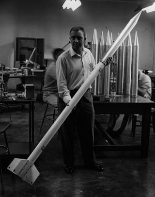 James Van Allen of the University of Iowa, posing with a rocket model.