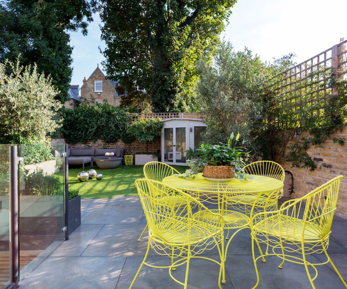 A garden path with porcelain tiles and yellow table and chairs