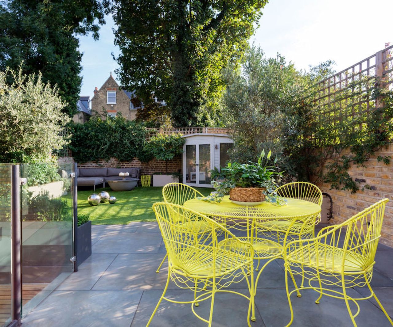 A garden path with porcelain tiles and yellow table and chairs