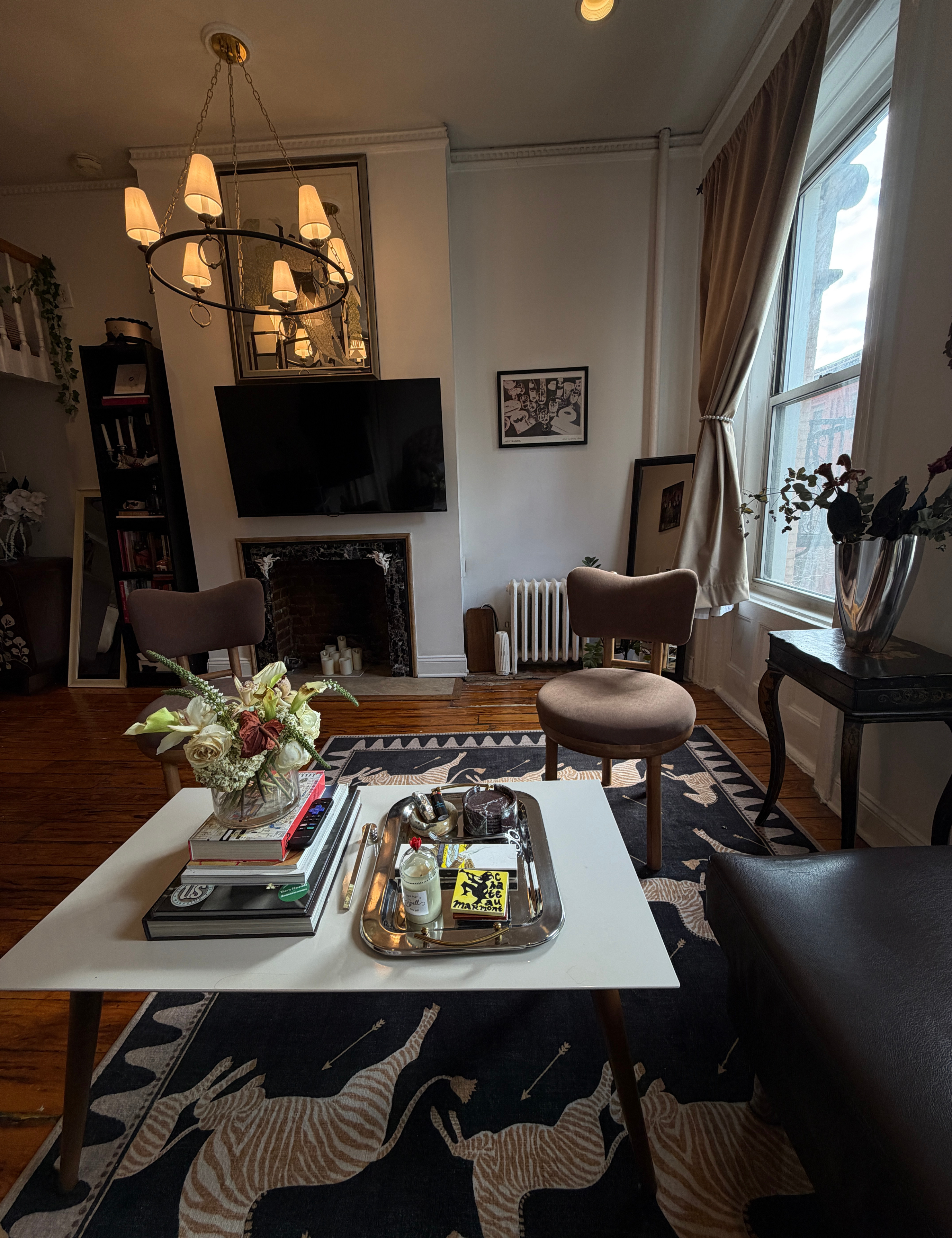 NYC living room featuring hardwood floors, a multi-shade circular chandelier, and a whimsical zebra motif area rug