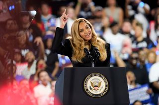 Beyonce speaks onstage at the Kamala harris rally wearing a black blazer dress