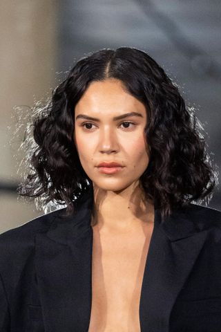 A model with a curly bob hairstyle with light shinning from behind.