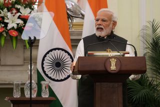 Modi gives a speech with the Indian flag in the background