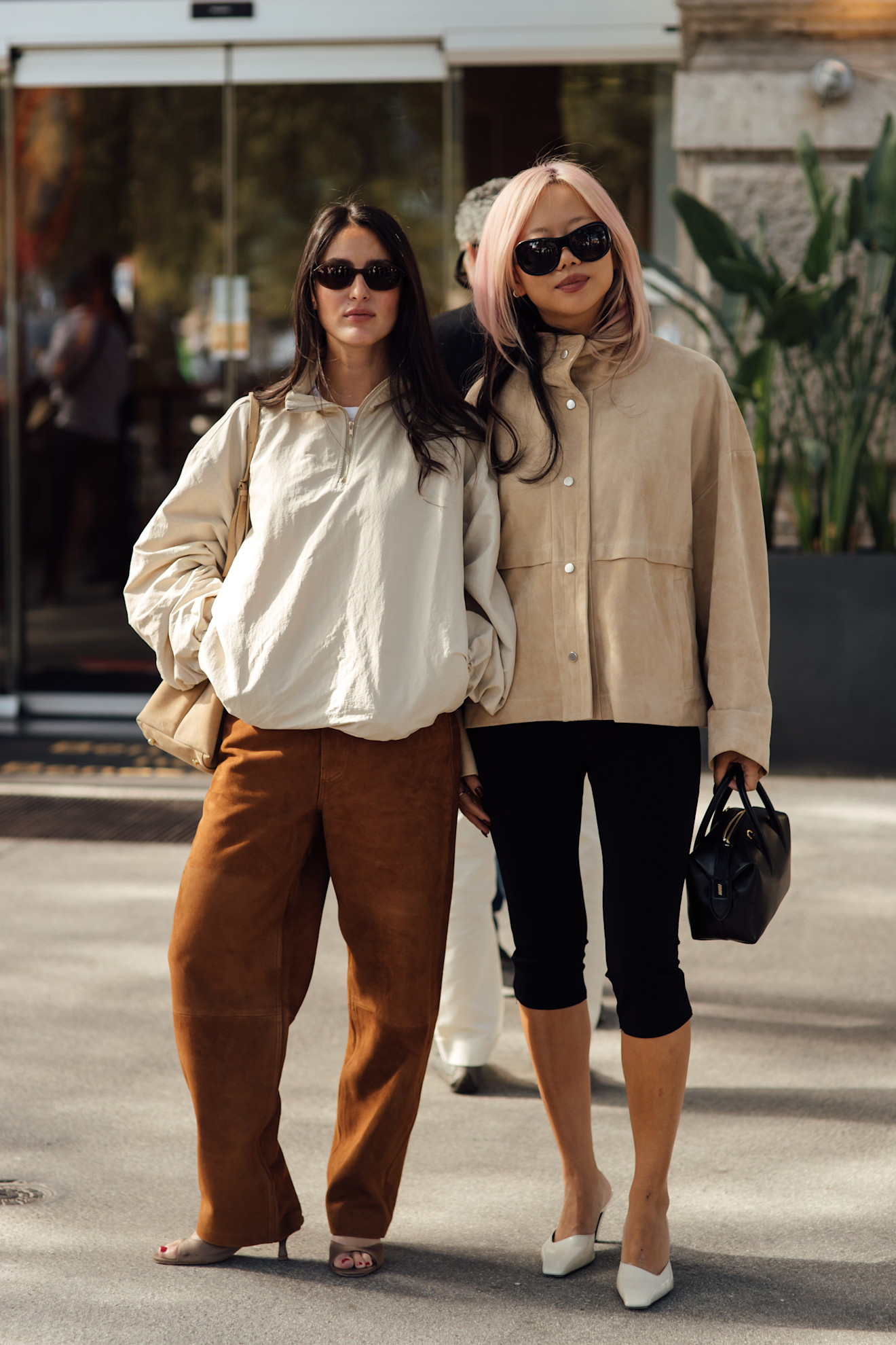 woman wearing funnel-neck jacket and capri pants; woman wearing windbreaker and brown pants