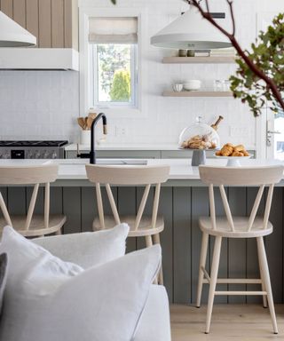 white kitchen with grey island, wooden stools and a matt black tap