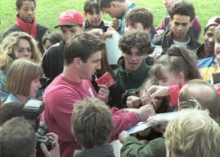 French soccer star Eric Cantona(C) signs autographs for youngsters from a team from South-West France who watched their hero train with the reserves before starting his first day of community service 18 April, at Manchester United's training ground. Cantona was found guilty after attacking a Crystal Palace fan.