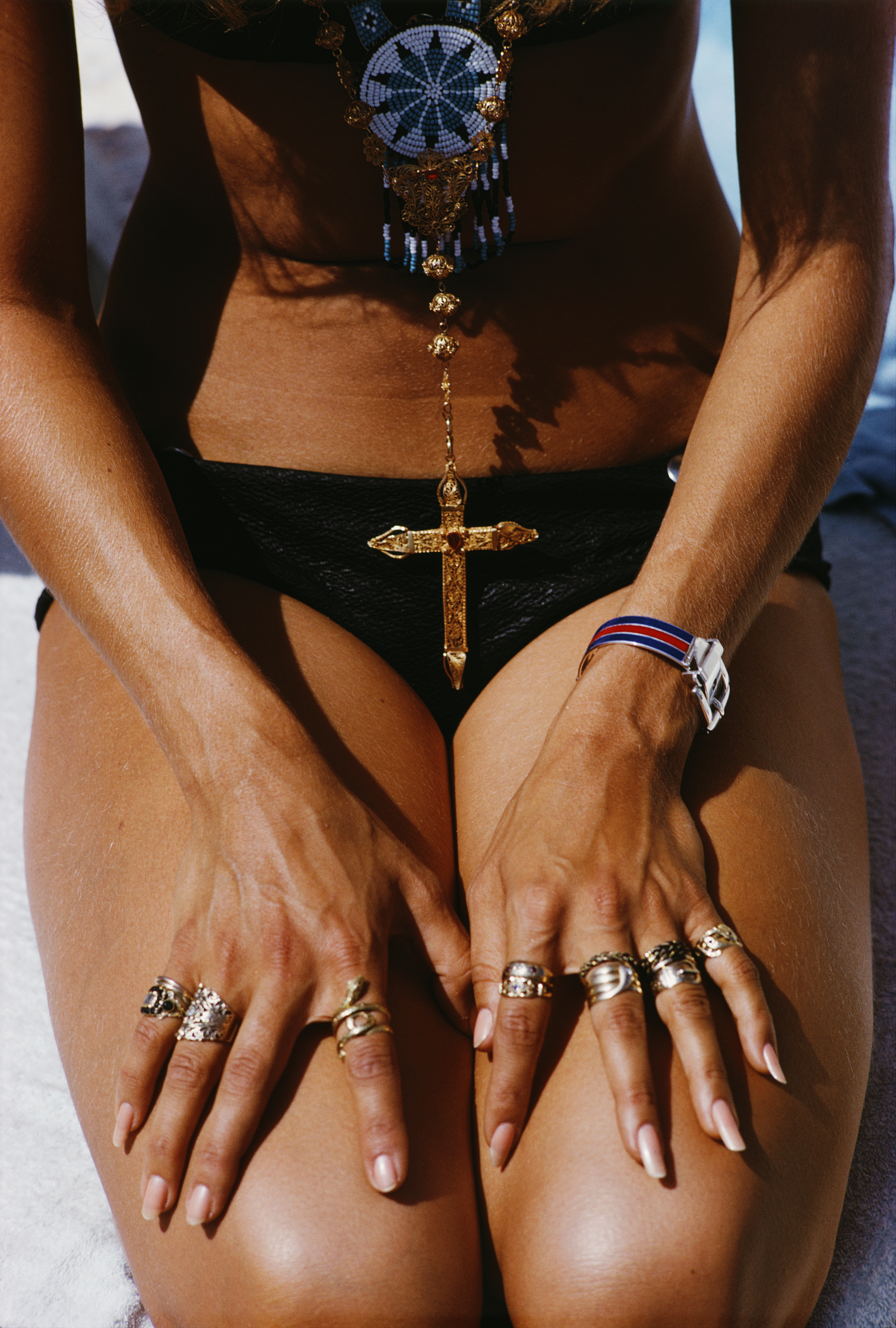 Body shot of a woman in a black bikini and large cross necklace