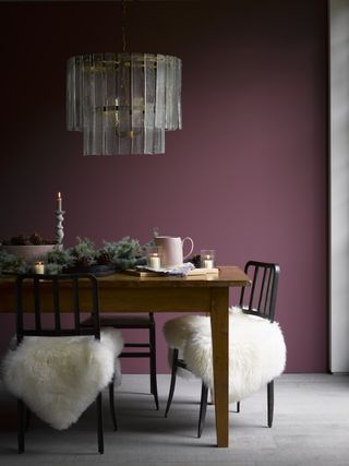 A festive Christmas-themed dining area with dining chairs covered with faux fur rugs and Christmas chandelier