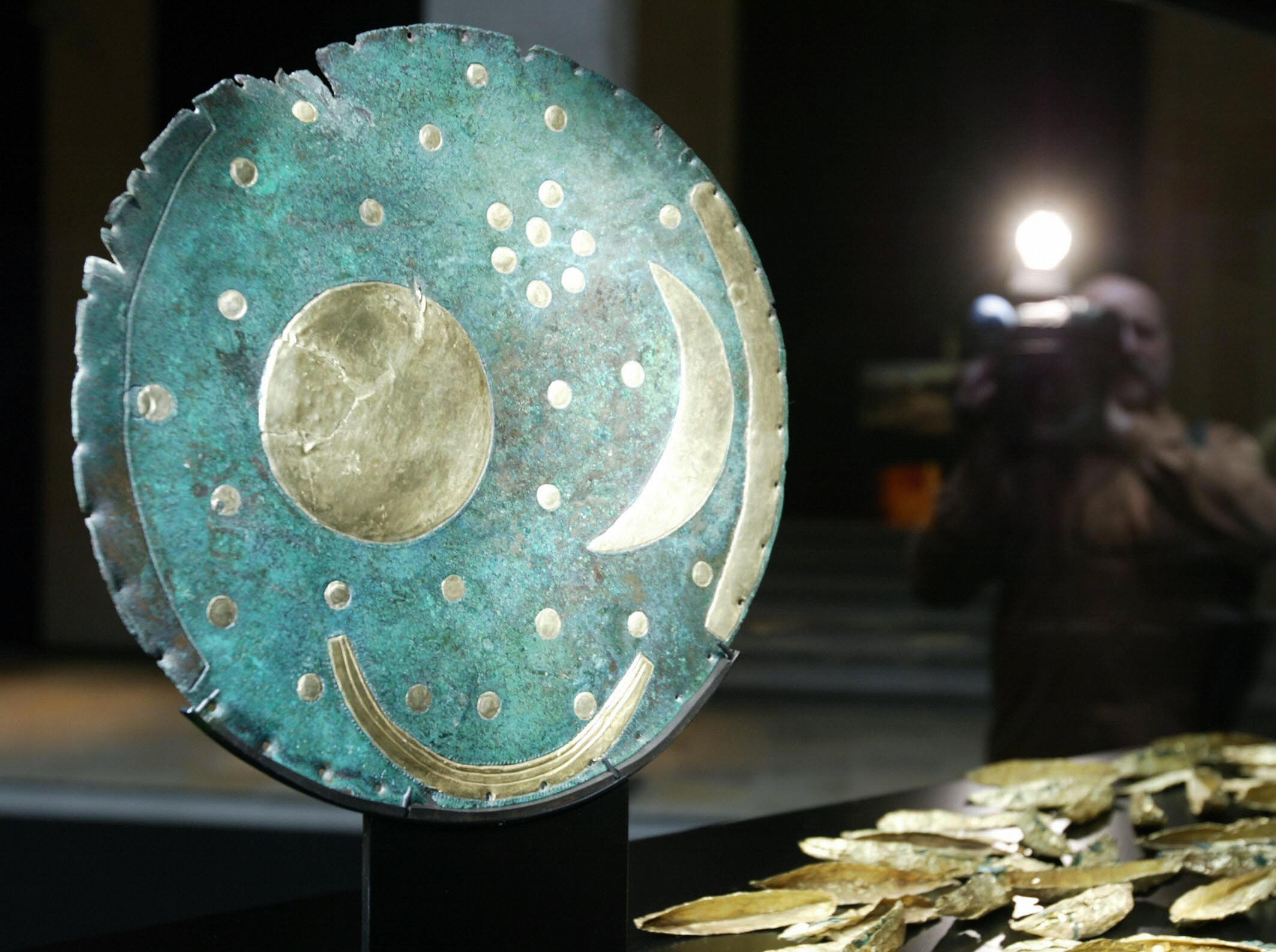 a large disc with shapes showing the moon and the sun and other points and lines that could be stars or other things