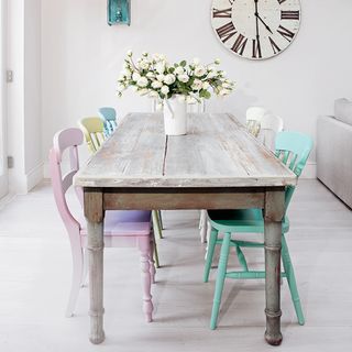dining area with wooden table and chairs with flower on vase