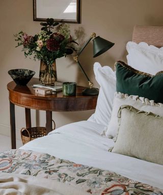 Esme Embroidered Quilt on a bed against a beige wall.