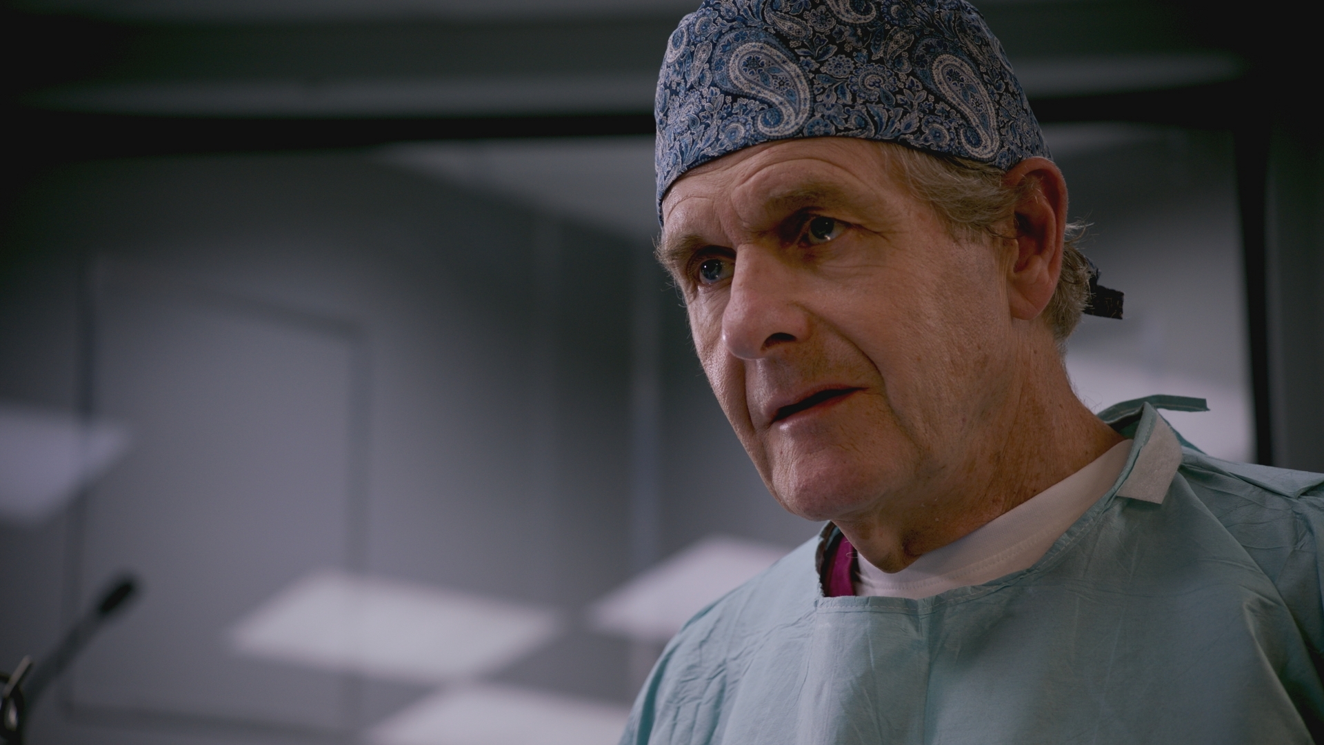 Russell Whitelaw in scrubs looking serious.