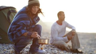 A couple cooking on a camping stove
