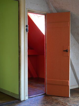 A doorway into a room with green walls next to a doorway to a room with pink walls.
