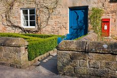 A cottage and postbox in Edensor, the estate village at Chatsworth, Peak District, Derbyshire.