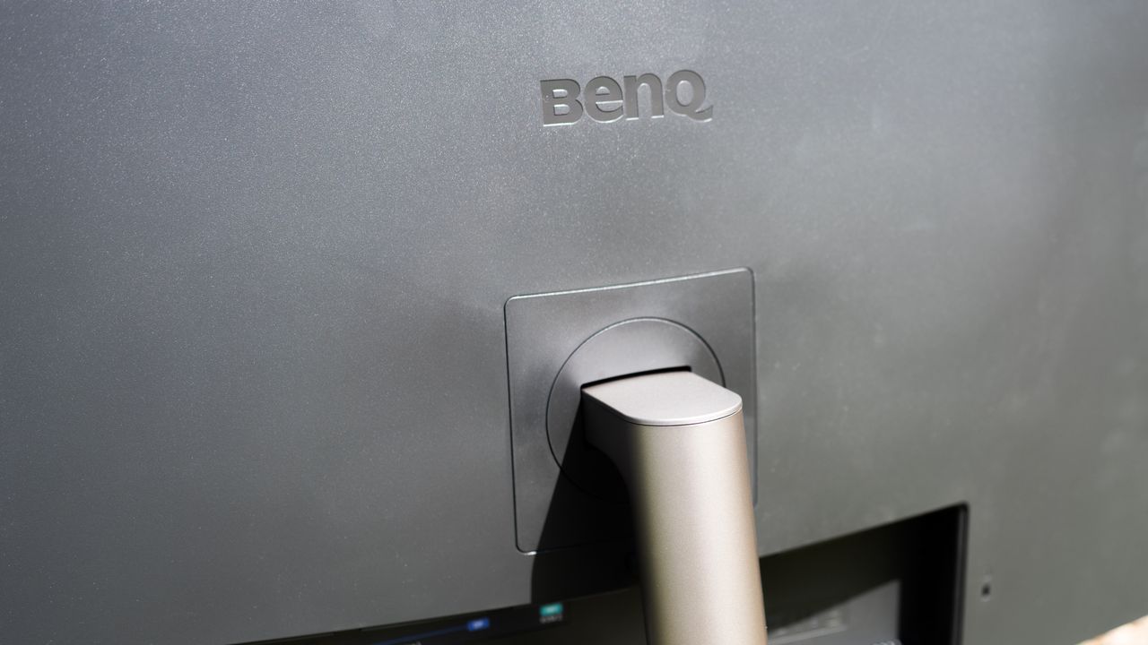 A black BenQ PD3225U monitor sitting on grass in sunshine