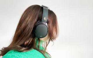 A pair of black Edifier WH950NB over-ear headphones photographed against a blue background