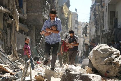 Men carry babies from scene of attack by Syrian government in Aleppo