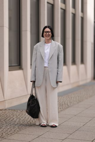 BERLIN, GERMANY - MARCH 31: Maria Barteczko seen wearing Victoria Beckham black oversized Aviator glasses, Arket white cotton basic t-shirt, Source Unknown grey linen oversized blazer, The Row beige silk wide leg pants, Chanel 22 black logo hobo shopper bag and Hermès white Chypre leather sandals, on March 31, 2024 in Berlin, Germany. (Photo by Jeremy Moeller/Getty Images)