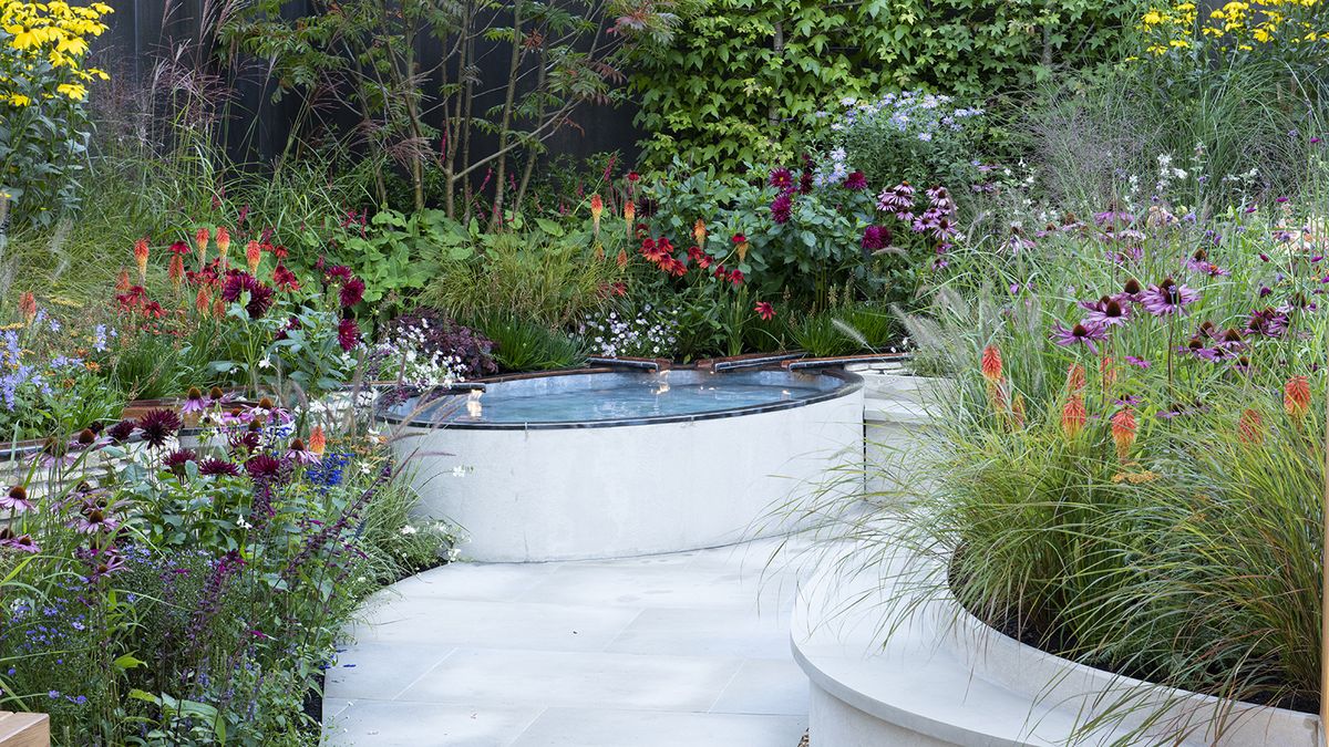 A curved garden space with water feature and bright planting