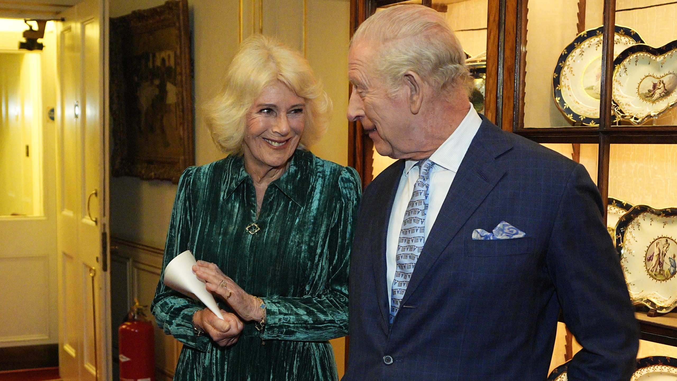 Queen Camilla and King Charles III smile as they attend a reception for authors, members of the literary community and representatives from the Queen's Reading Room on March 25, 2026