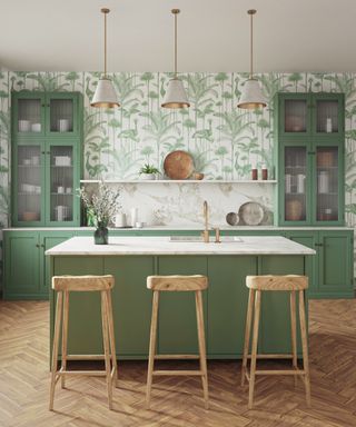 green and white kitchen with herringbone laid floor, island with sink and bar stools, green leaf wallpaper, marble countertops, countertop cabinets, trio of pendant lights, shelving