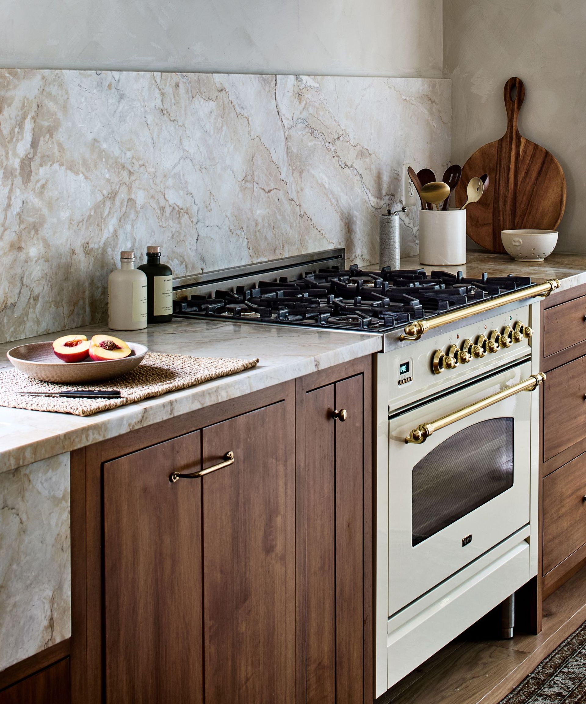 A wooden kitchen with marble countertops decorated with a wooden cutting board, ceramic canisters, and natural weave placemats