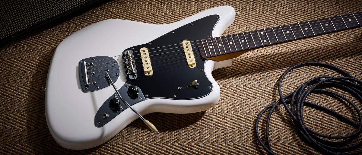 A Fender Player II Jaguar lying on the floor with a guitar cable