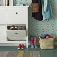 Shoes and boots lined up in a hallway with floral wallpaper