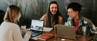 Three people with laptops around a table