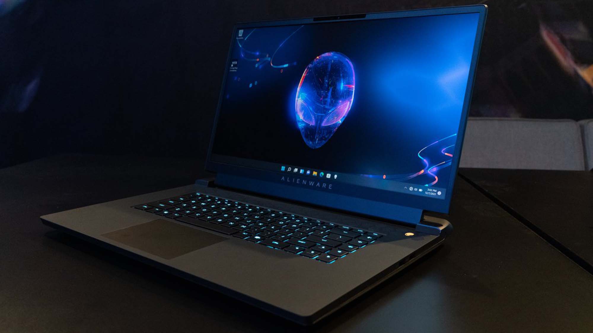An Alienware gaming laptop sitting on a table in a darkened room