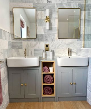 a double sinkwith a towel storage unit in gray and gold bathroom