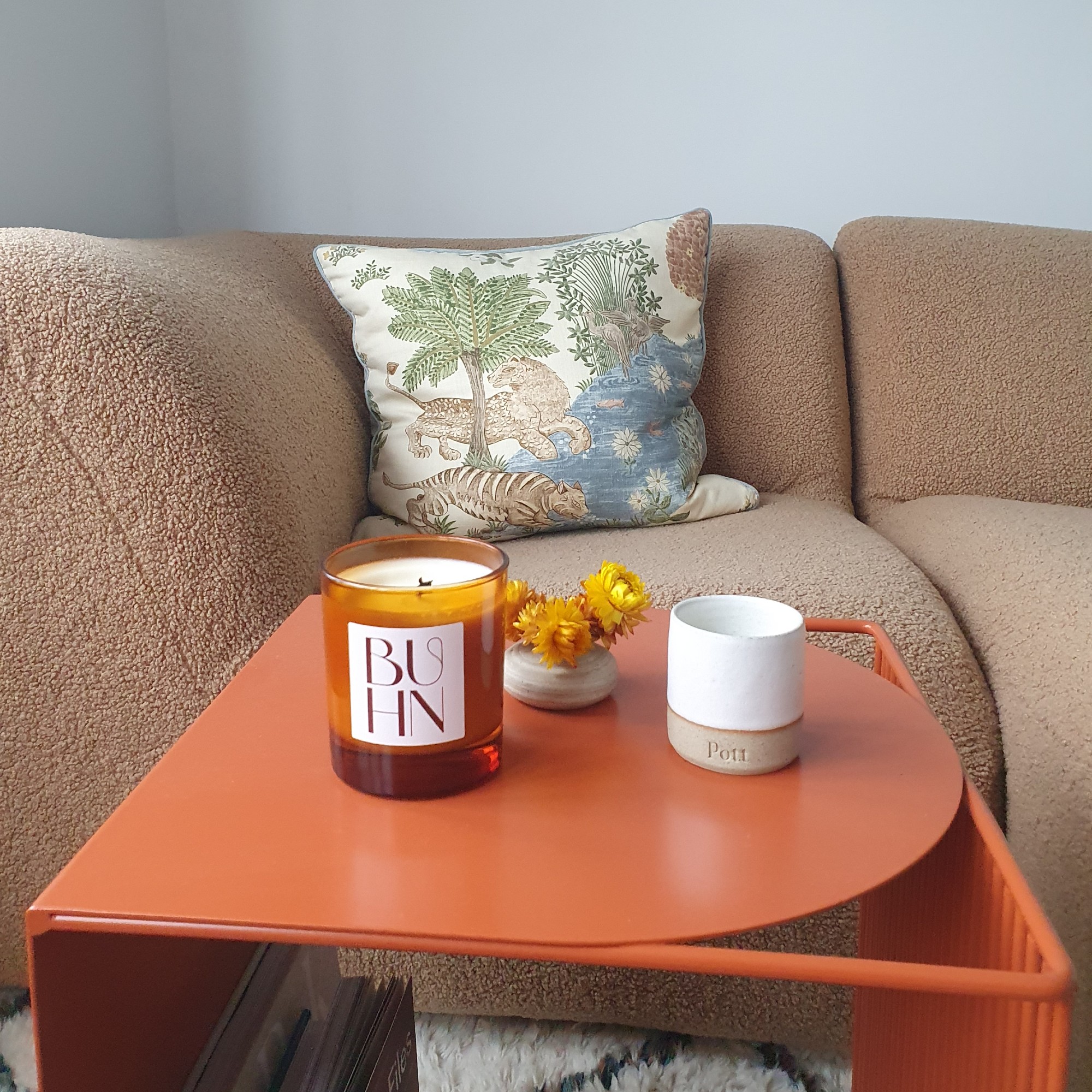 Sara's living room with a beige sofa and a terracotta orange coffee table displaying two refillable candles from Buhn and Pott
