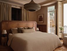 a burl bed in the center of a neutral bedroom with sophisticated linen sheets