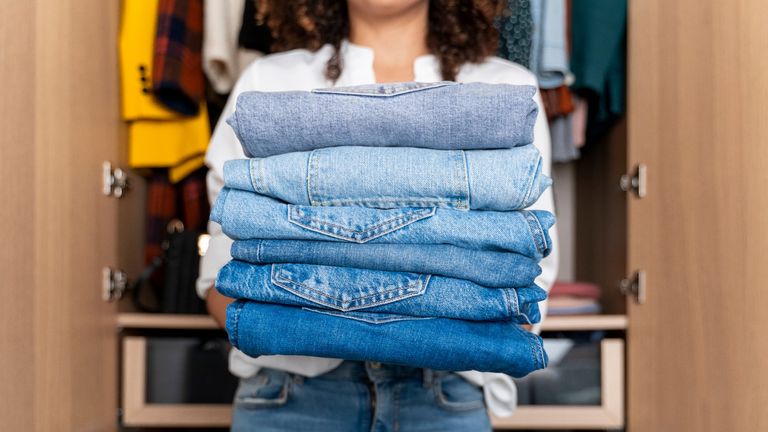 longest lasting jeans: woman holding a pile of jeans