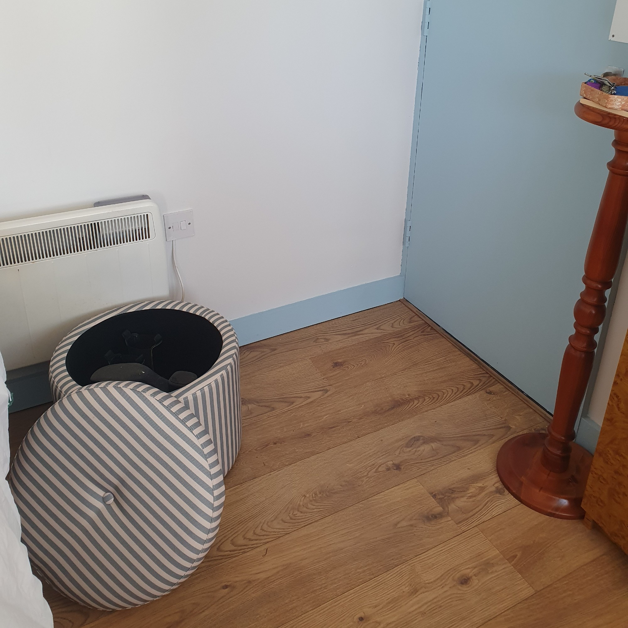 Sara's entrance area with a side table next to a blue front door and an open striped storage ottoman