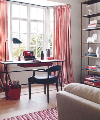 Living room with striped red and white curtains and desk in window