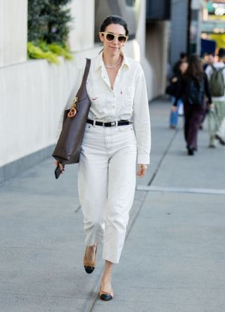 A woman wearing a white shirt, trousers and Chanel ballet pumps.