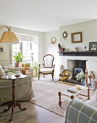 Cottage living room with small woodburning stove cream sofa and wood framed armchair and sisal rug