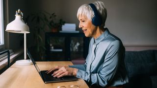 A lady at her laptop wearing headphones making music