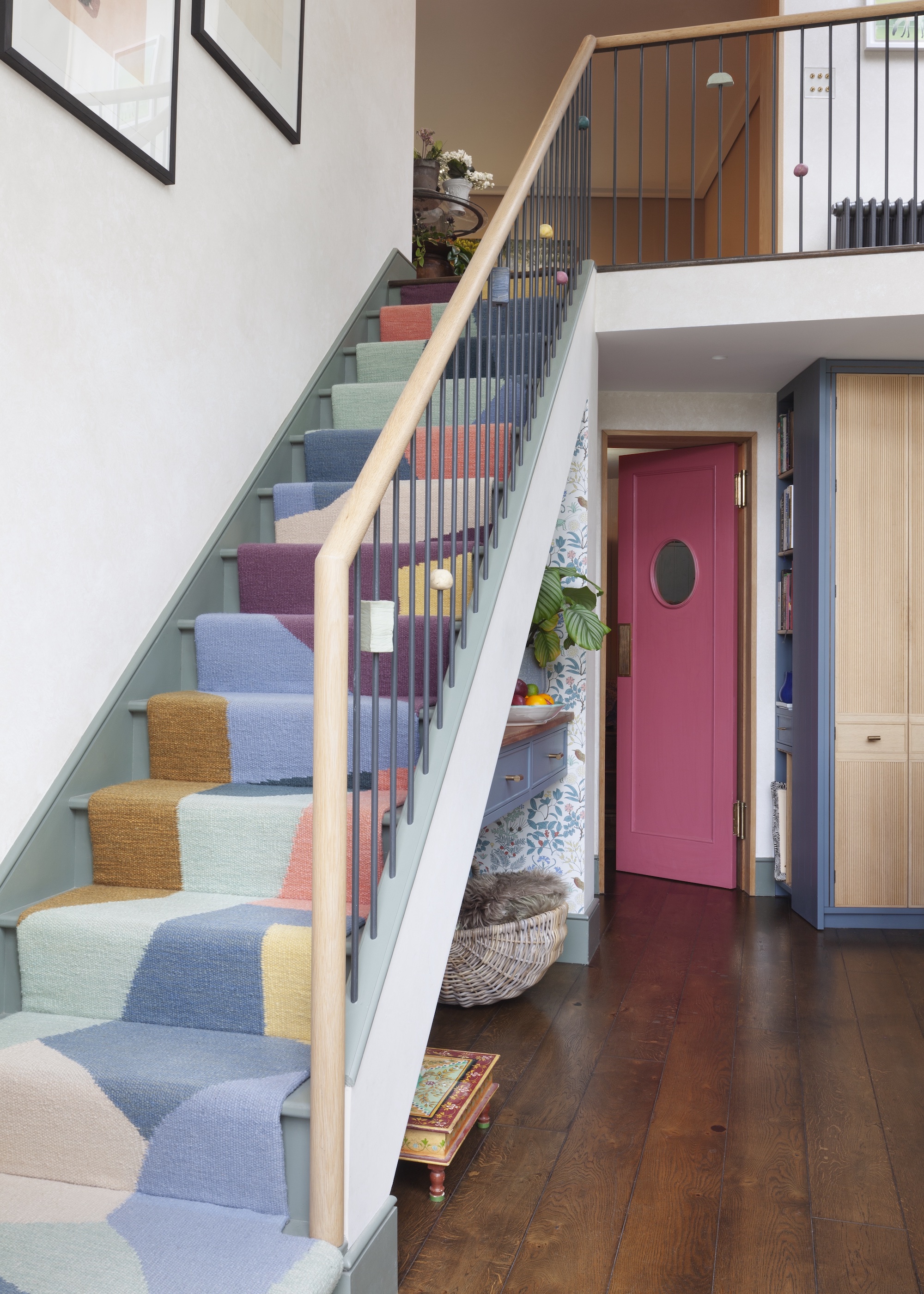 staircase with colourful patterned runner, there's a pink door in the background