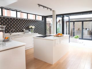A kitchen with a white kitchen island and a garage conversion beyond.