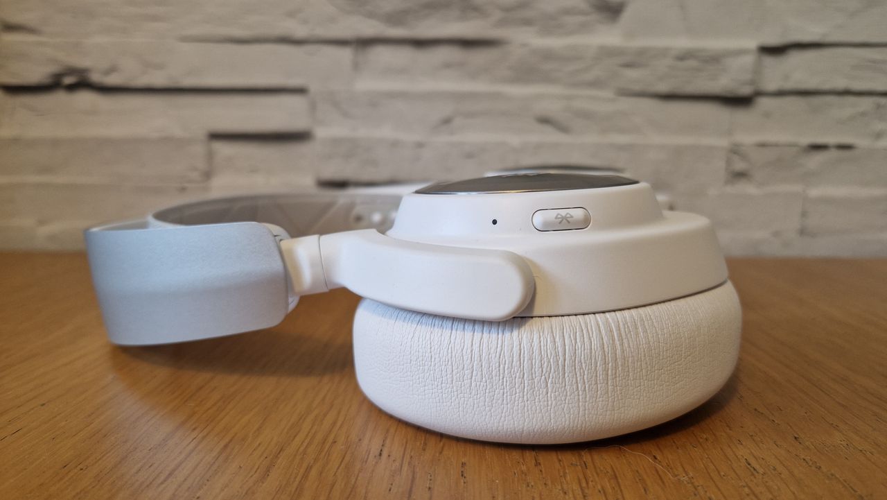 The SteelSeries Arctis Nova Pro Wireless white edition on a wooden surface with a white brick background