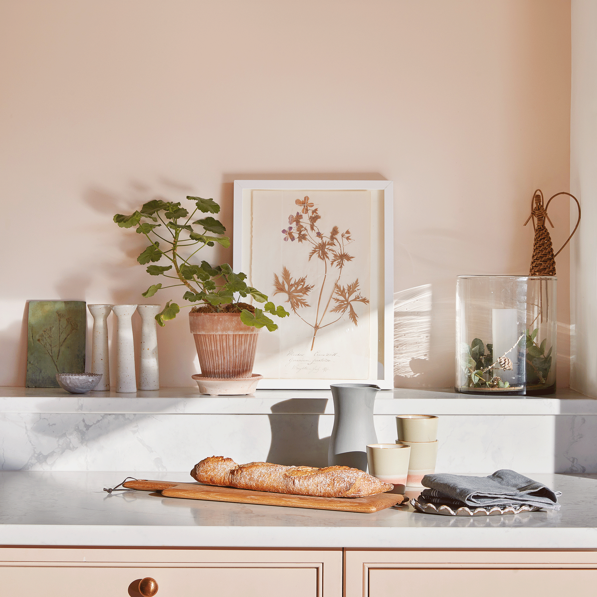 Pink kitchen with plaster pink walls, marble worktop and clay pots on worktop