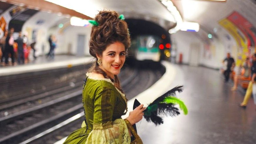 Woman dressed as Marie-Antoinette waiting for a train on the Pairs Metro.