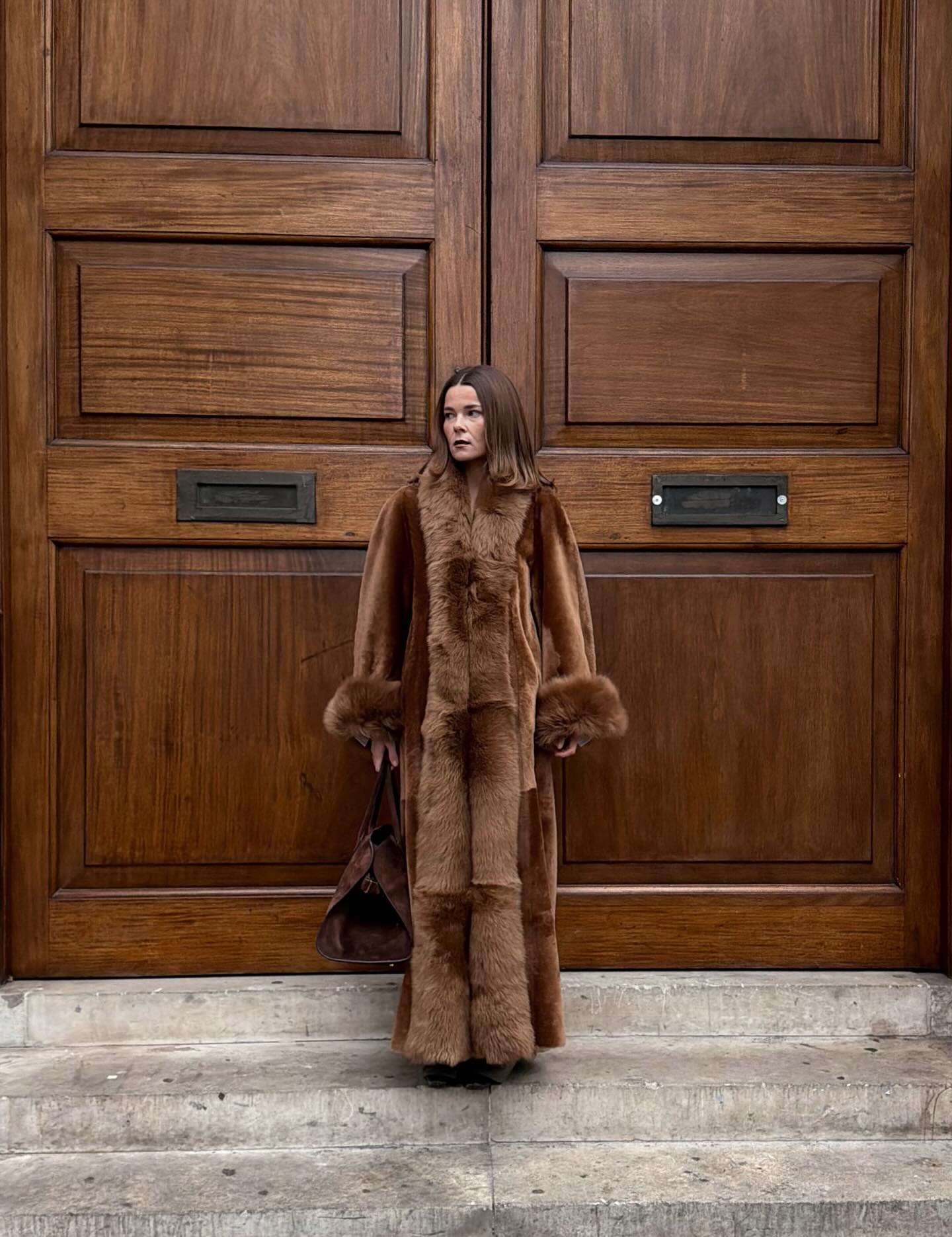 Street style photo of woman wearing a long fur coat.