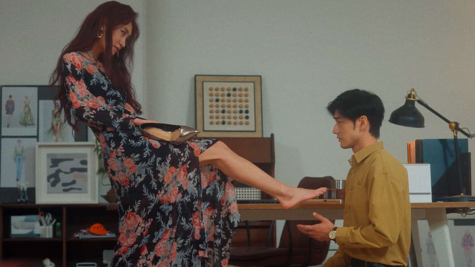A woman in a floral dress extends her bare foot to a kneeling man, in a screenshot from Chinese FMV game Revenge on Gold Diggers.