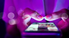 Close-up of a woman's hands holding her phone and scrolling in the dark
